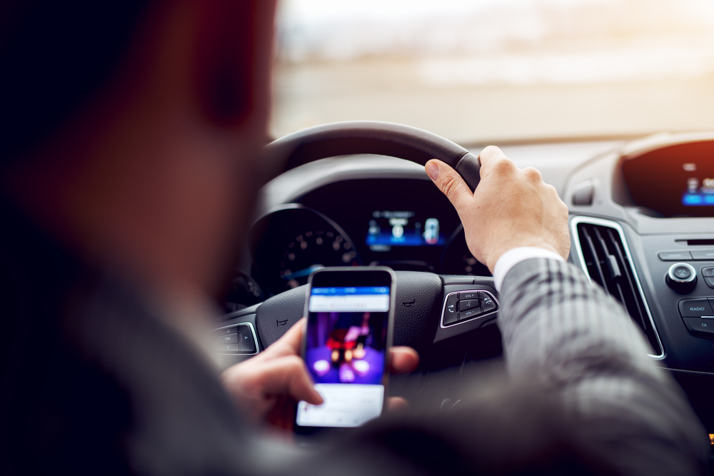 man looking at phone while driving